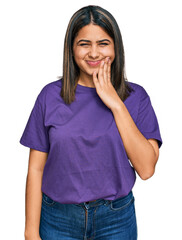 Wall Mural - Young hispanic girl wearing casual purple t shirt touching mouth with hand with painful expression because of toothache or dental illness on teeth. dentist