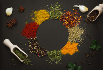 Wall Mural - Circle frame composition of spices and herbs isolated on dark background with copy space. Frame of Indian spices and herbs. Ingredients of asian cuisine spices