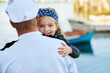 Father, child and marine uniform with hug or sailor captain at ocean for service duty, reunion or embrace. Man, daughter and happiness greeting for travel return or patriotic hero, family or navy