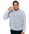 © Krakenimages.com - Young handsome hispanic man wearing casual sweatshirt smiling doing phone gesture with hand and fingers like talking on the telephone. communicating concepts.