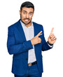 © Krakenimages.com - Young hispanic man wearing business jacket pointing aside worried and nervous with both hands, concerned and surprised expression
