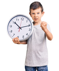 Wall Mural - Cute blond kid holding big clock annoyed and frustrated shouting with anger, yelling crazy with anger and hand raised