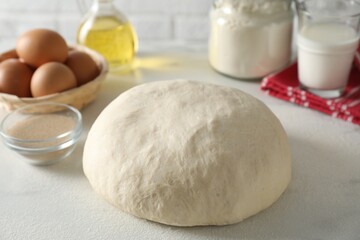 Raw dough and ingredients on white table