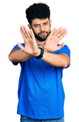 Poster - Young arab man with beard wearing casual blue t shirt rejection expression crossing arms doing negative sign, angry face