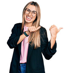 Wall Mural - Hispanic young woman wearing business jacket and glasses pointing to the back behind with hand and thumbs up, smiling confident