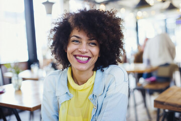 A woman with a smile on her face sitting at a table.