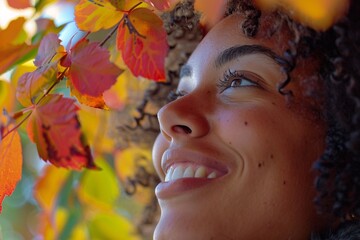 Wall Mural - A close-up shot of a woman's face as she laughs joyfully, her eyes sparkling with happiness, with colorful autumn leaves in the background, symbolizing joy and vitality