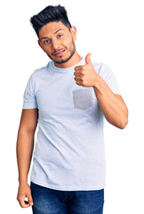 Wall Mural - Handsome latin american young man wearing casual clothes doing happy thumbs up gesture with hand. approving expression looking at the camera showing success.