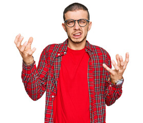 Wall Mural - Hispanic young man wearing casual clothes shouting frustrated with rage, hands trying to strangle, yelling mad