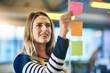 © peopleimages.com - Woman, sticky note and brainstorming project in office as company growth or market research, glass wall or idea. Female person, hand and paper at creative agency or business campaign, target or goal