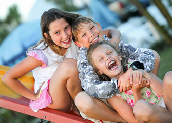 portrait of group of three laughing kids on playground