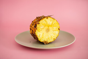 Wall Mural - A slice of pineapple is cut in half and placed on a white plate