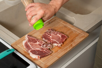 Wall Mural - A man is seasoning meat on a cutting board