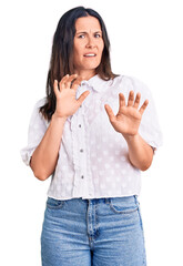 Wall Mural - Young beautiful brunette woman wearing casual shirt disgusted expression, displeased and fearful doing disgust face because aversion reaction. with hands raised