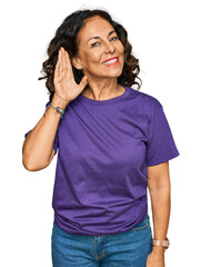 Poster - Middle age hispanic woman wearing casual clothes smiling with hand over ear listening an hearing to rumor or gossip. deafness concept.