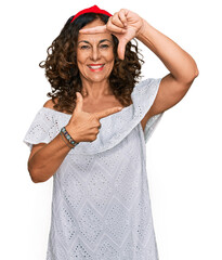 Sticker - Middle age hispanic woman wearing casual clothes smiling making frame with hands and fingers with happy face. creativity and photography concept.