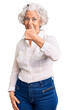 © Krakenimages.com - Senior grey-haired woman wearing casual clothes doing happy thumbs up gesture with hand. approving expression looking at the camera showing success.