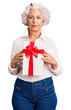 © Krakenimages.com - Senior grey-haired woman holding gift thinking attitude and sober expression looking self confident
