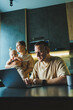 © DSMT - A young father works on a laptop while his wife takes care of the child. Work from home. A young couple in the kitchen with a child