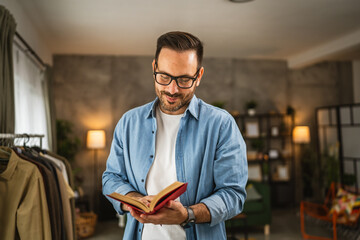 Wall Mural - Portrait of adult caucasian man with eyeglasses read book at living room happy and relax