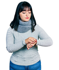 Poster - Young hispanic plus size woman wearing winter scarf checking the time on wrist watch, relaxed and confident