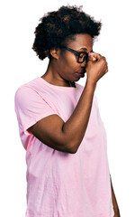 Wall Mural - African american woman with afro hair wearing casual clothes and glasses tired rubbing nose and eyes feeling fatigue and headache. stress and frustration concept.