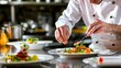 © Cassova - Professional chef carefully garnishing a dish with fresh herbs in a restaurant kitchen.