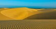 The Maspalomas Dunes in Gran Canaria offer a stunning view of the turquoise Atlantic waters against the contrasting sand dunes. The sunset views are equally impressive.