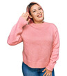 © Krakenimages.com - Hispanic woman with pink hair wearing casual winter sweater waiving saying hello happy and smiling, friendly welcome gesture