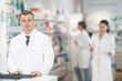 © JackF - Attentive young man apothecary standing at the stand with his hand on keyboard in big pharmacy