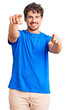 © Krakenimages.com - Young handsome man with curly hair wearing casual clothes pointing to you and the camera with fingers, smiling positive and cheerful