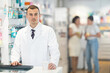 © JackF - Positive young male pharmacist standing at the desk using keyboard in chemist's shop