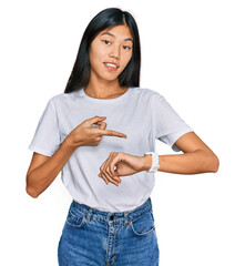 Poster - Beautiful young asian woman wearing casual white t shirt in hurry pointing to watch time, impatience, upset and angry for deadline delay