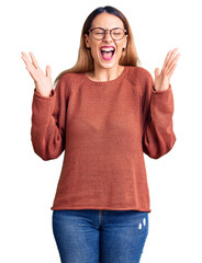 Wall Mural - Beautiful young woman wearing casual clothes and glasses celebrating mad and crazy for success with arms raised and closed eyes screaming excited. winner concept