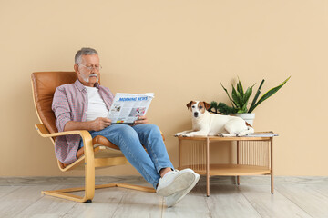 Wall Mural - Mature man with cute Jack Russell terrier reading newspaper in armchair at home