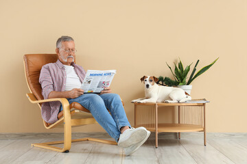 Poster - Mature man with cute Jack Russell terrier reading newspaper in armchair at home