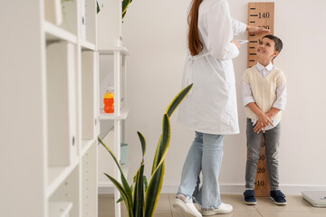 Sticker - Pediatrician measuring height of cute little boy near wooden stadiometer in clinic