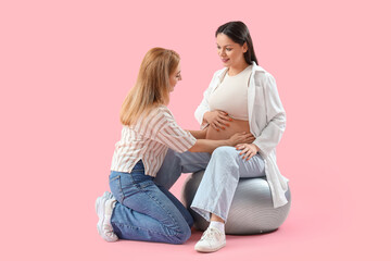 Sticker - Mature doula and pregnant woman sitting on fitball against pink background