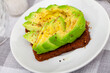 Open avocado sandwich with rye bread served on plate for breakfast or lunch. Healthy vegan snack..