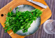 Parsley sprigs on plate, on wooden table. Food ingredient, preparing food concept.