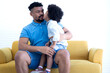 Loving African boy kissing his father on yellow sofa at home, Happy Father's Day