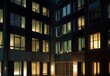 Nighttime office exterior, windows aglow with energy-efficient lighting, generative AI