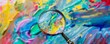 © CHONCHANOK PHOTO - A magnifying glass revealing a hidden message within a swirling paint splatter, highlighting the discovery of creative ideas in the unexpected