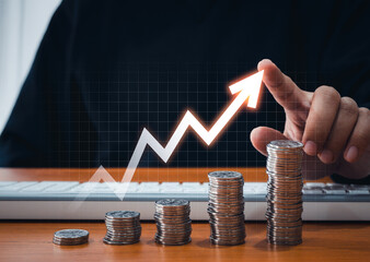 Growing up volatility arrow draw by businessman hand on coins stacked as bar graph chart steps on online network screen. Investment, income, inflation, business growth, economic improvement concepts.