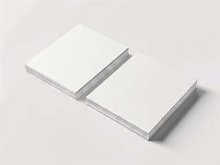 Two white blank books on a white surface.