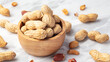 Roasted peanuts in shell in wooden bowl on white marble table