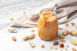 Peanut butter in glass jar with spoon on white marble table