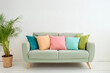 © Mariusz Blach - Colorful pillows on sofa in the living room at home. Blue sofa on wooden floor against white wall with copy space