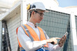 Asia Man engineer using tablet computer at rooftop building construction or working checking HVAC and installing large air conditioning system	