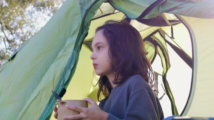 Sticker - boy in summer camp. child has breakfast in the mountains. child eats in a tent. boy in a sleeping bag with a plate in his hands. camping and trekking with children.